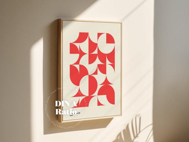 May include: A framed print with a geometric design featuring red and white shapes. The print is titled "DIN A Ratio" and is hanging on a white wall.