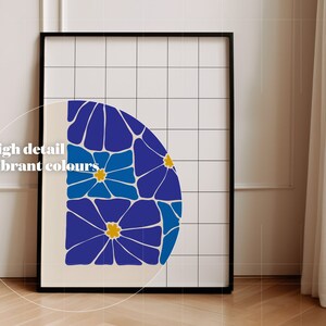 May include: A framed print with a geometric design of blue and yellow flowers on a white background. The print is framed in black and has a white grid pattern behind the image.