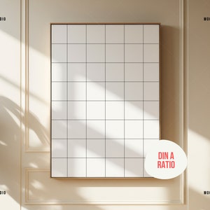 K&ouml;nnte beinhalten: Ein wei&szlig;er gerahmter Leinwand-Mockup mit einem Rastermuster, der an einer beigefarbenen Wand mit wei&szlig;en Leisten h&auml;ngt. Die Leinwand ist im DIN A-Format. Die Wand hat einen Schatten von einem Fenster.