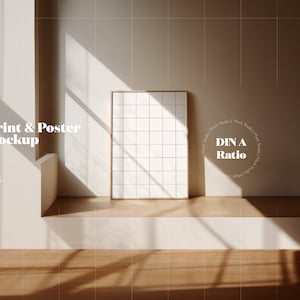 Puede incluir: Una maqueta de póster blanco en un marco de madera, sentada en una repisa blanca con un suelo de madera. El póster está en una proporción DIN A. El texto "Print & Poster Mockup" está en la esquina superior izquierda de la imagen. El texto "PSD, JPG, PNG" está debajo del texto "Print & Poster Mockup".