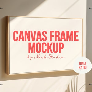 May include: A mockup of a canvas frame with a wooden frame. The frame is hanging on a wall and the text "CANVAS FRAME MOCKUP by Mock Studio" is written in red on the canvas. The text "DIN A RATIO" is written in white on a white circle in the bottom right corner of the canvas.