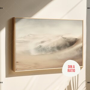 May include: A framed print of a desert landscape with sand dunes and a hazy sky. The frame is a light wood colour. The print is in a DIN A ratio.