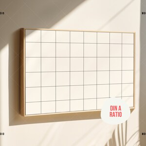 May include: A white gridded board with a wooden frame, hanging on a beige wall. The board is in a DIN A ratio. The board is illuminated by sunlight.