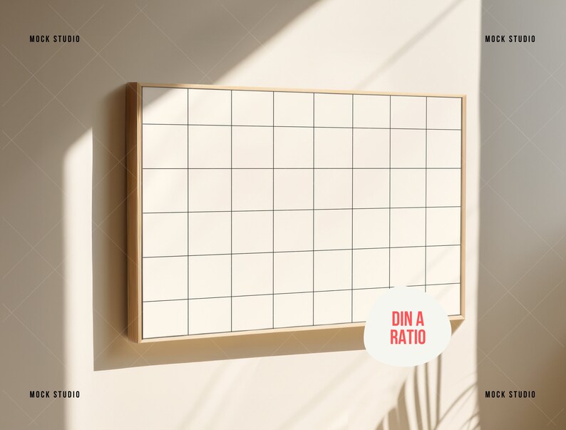 May include: A white gridded board with a wooden frame, hanging on a beige wall. The board is in a DIN A ratio. The board is illuminated by sunlight.