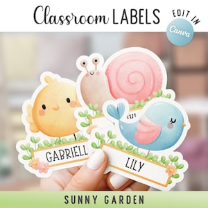 Può includere: Etichette per la classe con illustrazioni di un pulcino, una lumaca e un uccellino, tenute in mano. Le etichette hanno nomi e sono circondate da verde e fiori. È visibile anche il testo "Classroom Labels" e "Sunny Garden".