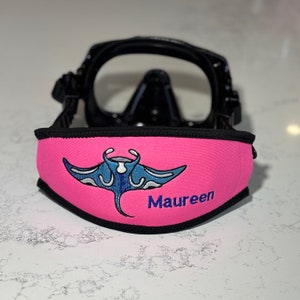 Puede incluir: Tira de máscara de buceo rosa con un diseño de manta raya azul y blanca y el nombre "Maureen" bordado.