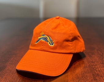May include: An orange baseball cap with an embroidered blue, yellow, and black sea slug design.