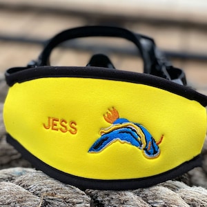 Yellow neoprene scuba mask strap with black trim and a blue and orange embroidered sea slug design. The strap is personalized with the name "JESS".