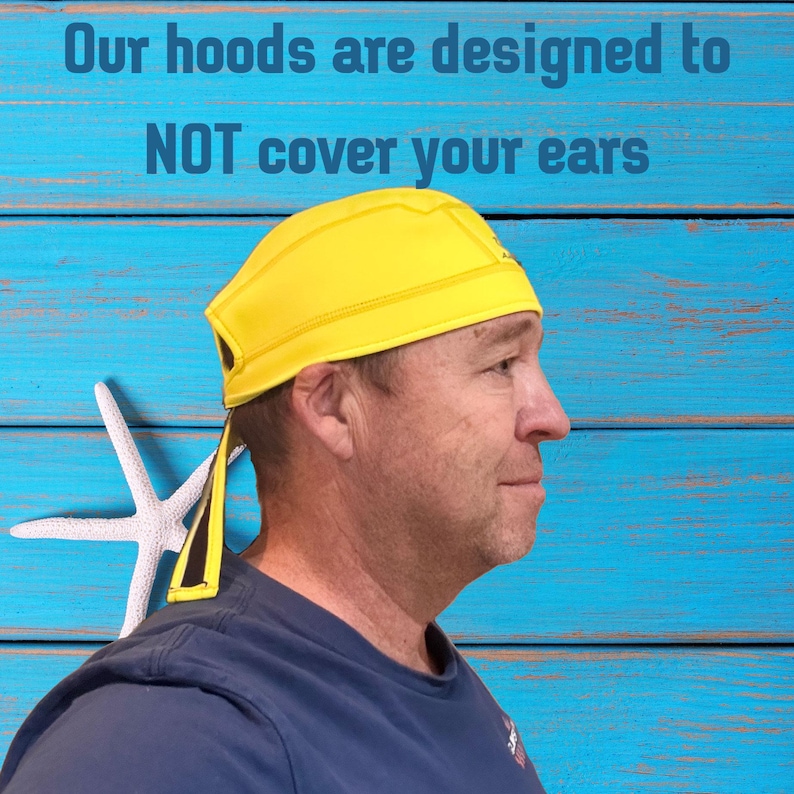 May include: A yellow hood, designed not to cover the ears, is worn by a person. The hood has a streamlined design and is made of a smooth material. The text "Our hoods are designed to NOT cover your ears" is displayed above the hood.
