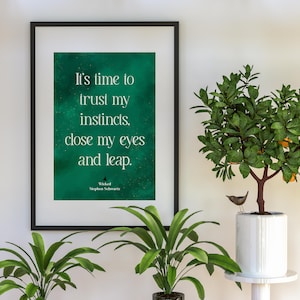 May include: A framed print with a green background and white text that reads "It's time to trust my instincts, close my eyes and leap." The text is attributed to "Wicked, Stephen Schwartz".