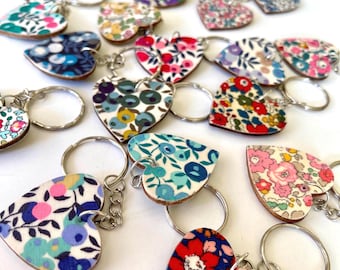 May include: A collection of colourful heart-shaped keyrings with floral patterns. Each keyring features a silver metal ring and a chain.