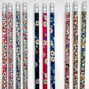 May include: Nine pencils with different floral patterned designs. The pencils are labeled with numbers 54-63. The pencils have silver colored tops with erasers.