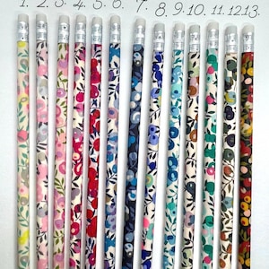 May include: A set of 13 pencils with different floral patterns. The pencils are all white with a black eraser and a silver band around the eraser. The pencils are numbered 1 through 13. The text "Collection Wiltshire" is at the top of the image.