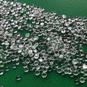 以下が含まれることがあります： 緑色の表面に散らばっている透明な丸いプラスチックビーズがたくさんある