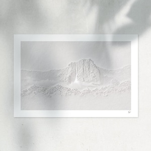 May include: A monochromatic white embossed art print featuring a textured mountain landscape with a central waterfall cascading down a cliff face. The relief design creates subtle shadows and depth, with a small signature mark in the bottom right corner.