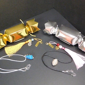 May include: Two gold and silver Christmas cracker boxes with tassels and necklaces with charms. The necklaces have blue and clear crystal pendants.