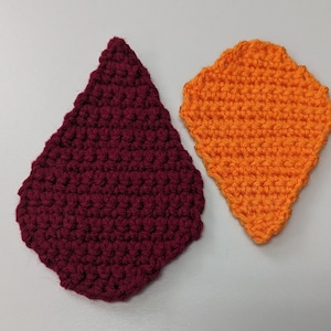 May include: Two crocheted shapes, one is a burgundy teardrop and the other is an orange diamond.