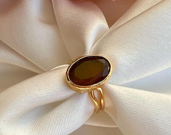May include: A gold ring with a large, oval-shaped, dark brown gemstone.