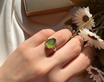 May include: A gold ring with a green oval-shaped stone set in a gold band.