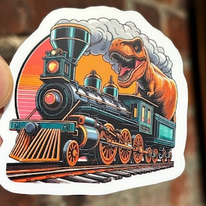 May include: A colourful sticker depicting a cartoon train with a T-Rex dinosaur emerging from the top. The train is black, teal, and gold, with a yellow and orange sunset background. The sticker is on a white background.