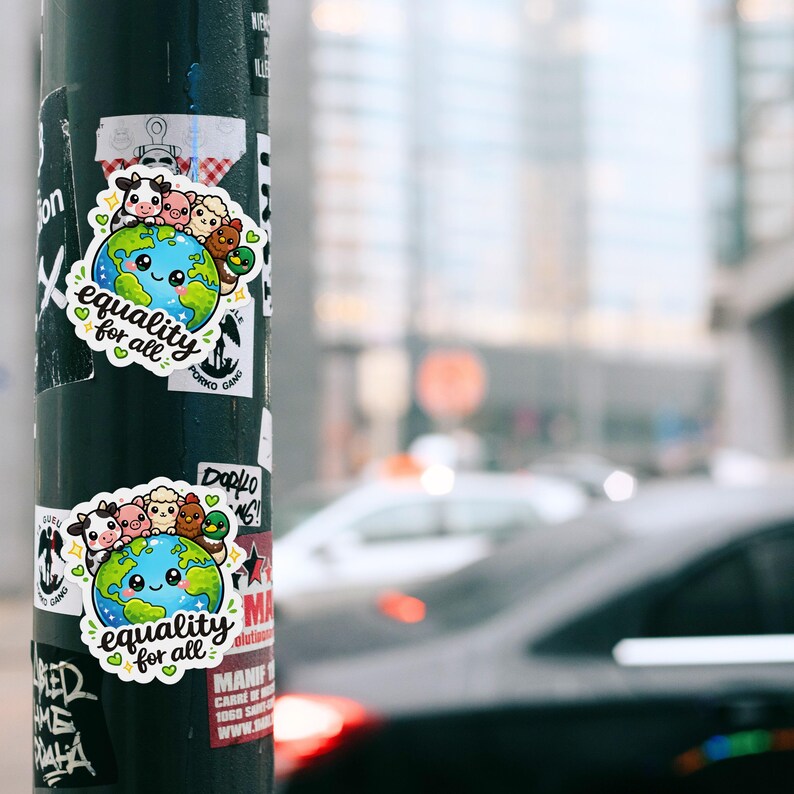 May include: A die-cut sticker featuring a cartoon Earth with a smiling face, surrounded by a cow, pig, sheep, chicken, and duck. The text "equality for all" is written in black cursive script below the globe, accented by small green hearts.