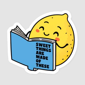 Könnte beinhalten: Ein gelber Zitronencharakter mit einem lächelnden Gesicht und rosigen Wangen liest ein blaues Buch. Der Buchumschlag trägt den Text "SWEET THINGS ARE MADE OF THESE" in schwarzen Großbuchstaben. Der Aufkleber hat einen weißen Rand.