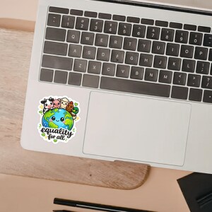 May include: A die-cut sticker featuring a cartoon Earth with a smiling face, surrounded by a cow, pig, sheep, chicken, and duck. The text "equality for all" is written in black script below the globe, accented by small green hearts and yellow stars.