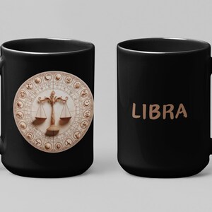 Puede incluir: Taza de cerámica negra con el símbolo del zodiaco Libra. Un lado muestra un diseño beige detallado de la balanza rodeado de símbolos del zodiaco. El otro lado tiene la palabra "LIBRA" en beige.