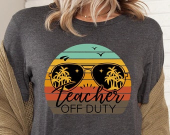 May include: A dark gray t-shirt with a retro-style graphic of sunglasses with palm trees and the text "Teacher Off Duty".