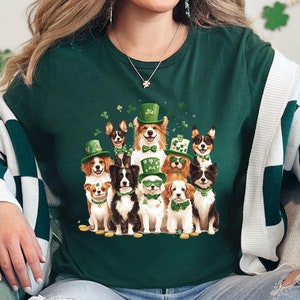 May include: Green t-shirt with a graphic of a group of dogs wearing shamrock hats and holding shamrocks. The dogs are all different breeds and sizes.
