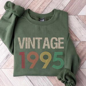 May include: A green sweatshirt with the text "Vintage 1995" in a retro, multi-colored font.