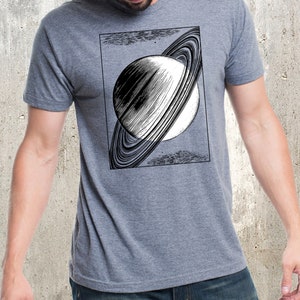 May include: A heather grey t-shirt with a black and white illustration of Saturn with its rings.