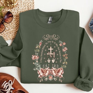 May include: A green sweatshirt with a floral design and the text "O Mary, Conceived Without Sin, Pray for Us Who Have Recourse to Thee."