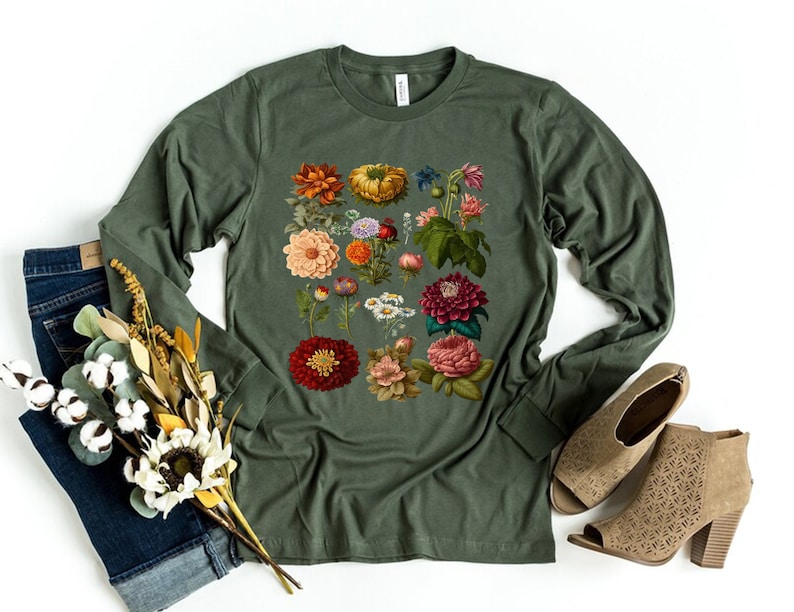 May include: A long-sleeved, olive green t-shirt with a vintage floral print featuring a variety of flowers in shades of red, pink, orange, yellow, and white.