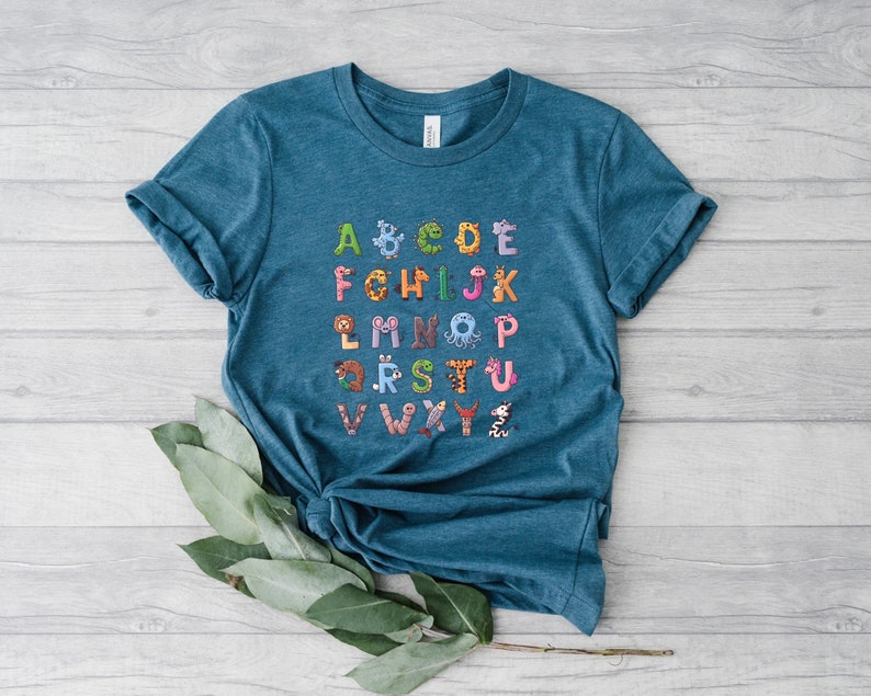 May include: A teal blue t-shirt with a colorful alphabet printed on the front. Each letter is decorated with a different animal illustration.