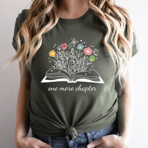May include: A green t-shirt with a white graphic of an open book with flowers growing out of it. The text "one more chapter" is printed below the book.