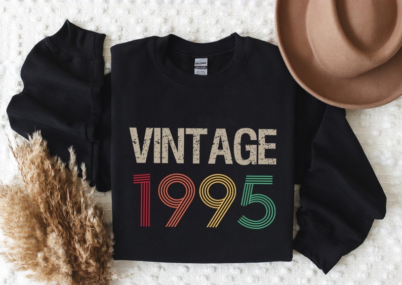 May include: Black sweatshirt with a vintage 1995 design in rainbow colors. The text "Vintage" is in a distressed font.