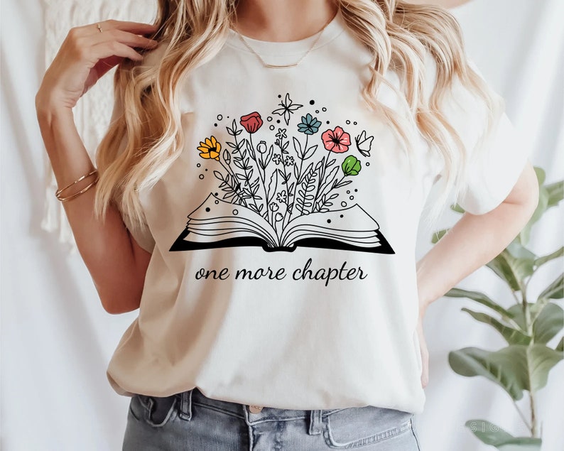 May include: White t-shirt with a black and white illustration of an open book with flowers growing out of it. The text "one more chapter" is printed below the book.