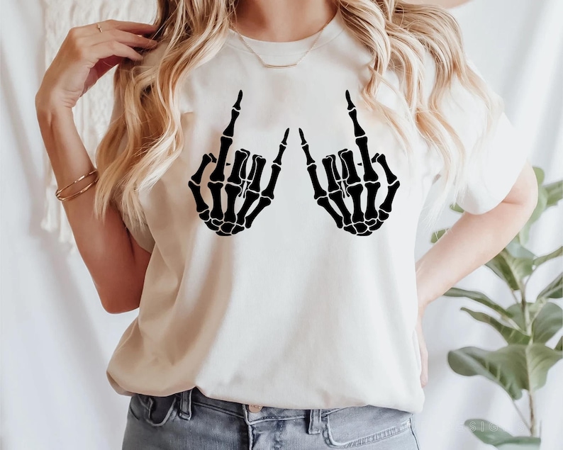 May include: White t-shirt with a black skeleton hand design making a rock and roll hand gesture.