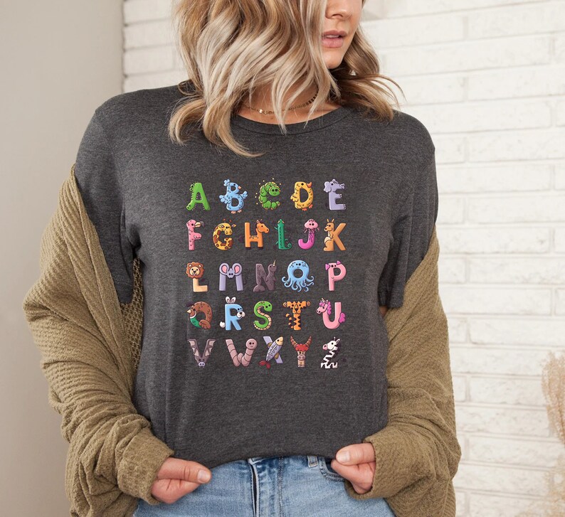 May include: A dark gray t-shirt with a colorful alphabet printed on the front. Each letter is formed by a different animal.