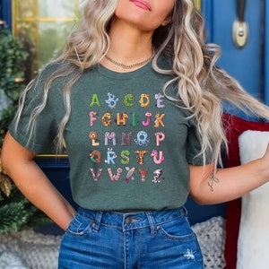 May include: A green t-shirt with a colorful alphabet printed on the front. Each letter is decorated with a different animal illustration.