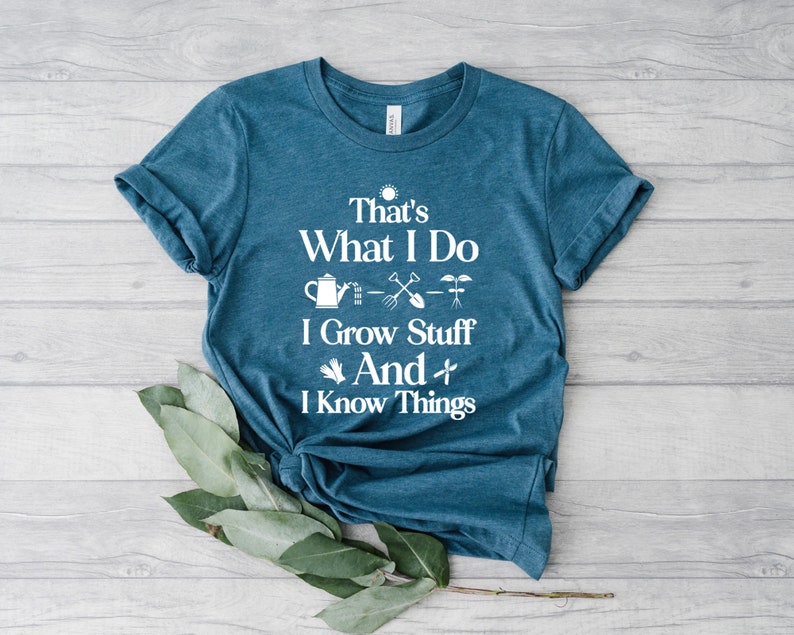 May include: A teal blue t-shirt with white text that reads "That's What I Do I Grow Stuff And I Know Things". The text is surrounded by gardening-themed icons.