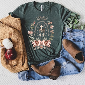 Op de afbeelding: Een groen T-shirt met een bloemenpatroon en de tekst "O Maria, onbevlekt ontvangen, bid voor ons die onze toevlucht tot u nemen".