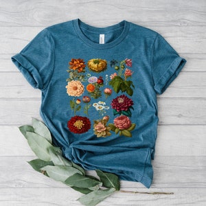 May include: A teal blue t-shirt with a floral print featuring a variety of colorful flowers, including red, orange, yellow, pink, and purple.
