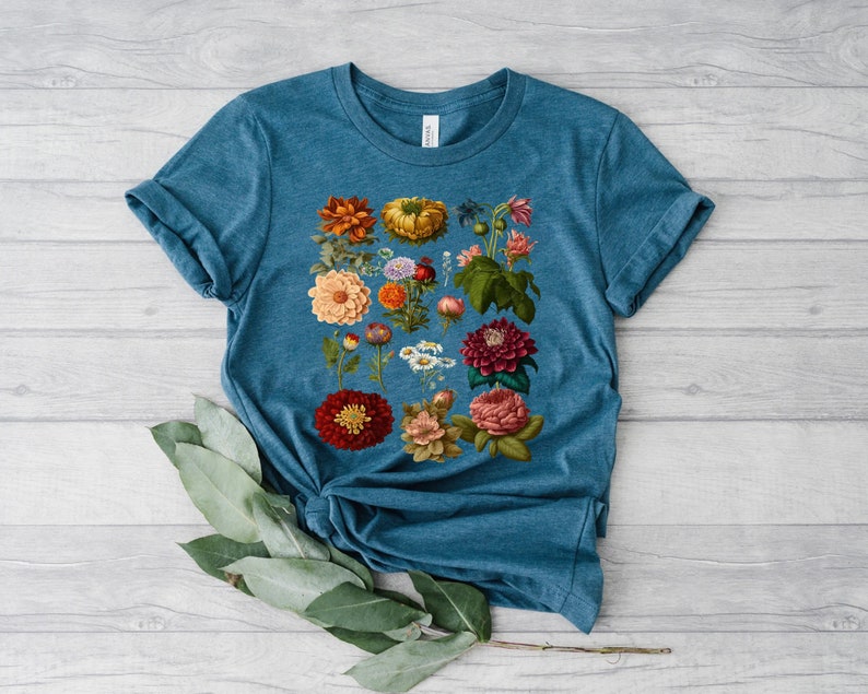 May include: A teal blue t-shirt with a floral print featuring a variety of colorful flowers, including red, orange, yellow, pink, and purple.