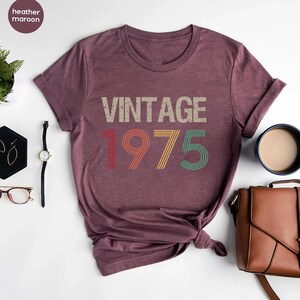 May include: Heather maroon t-shirt with a vintage-style graphic that says "Vintage 1975".