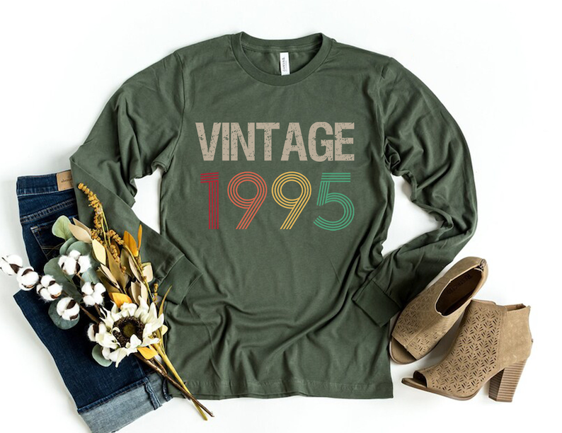 May include: A green long-sleeved t-shirt with the text "Vintage 1995" in a retro font with colorful accents.