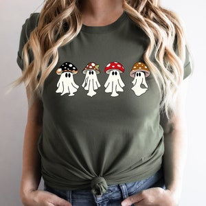 May include: A green t-shirt featuring a design of four ghosts wearing mushroom hats. The mushrooms are red, brown and black with white spots.