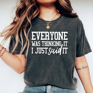 Pu&ograve; includere: Una maglietta grigia scura con il testo "Everyone was thinking it, I just said it" stampato in bianco.