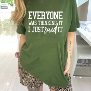 Pu&ograve; includere: Una maglietta verde con il testo "Everyone was thinking it I just said it" in lettere bianche.